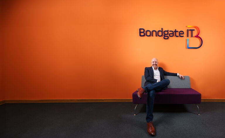 Garry Brown sat underneath the Bondgate IT Logo in front of an orange wall